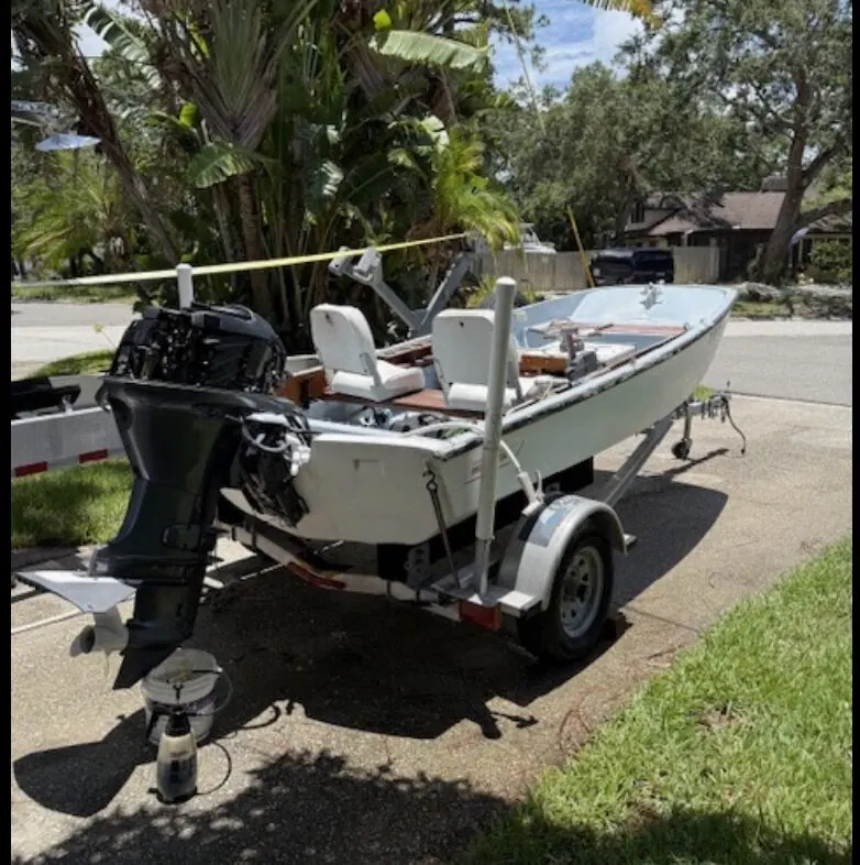 Small skiff on a trailer being serviced in a driveway with a flush kit
